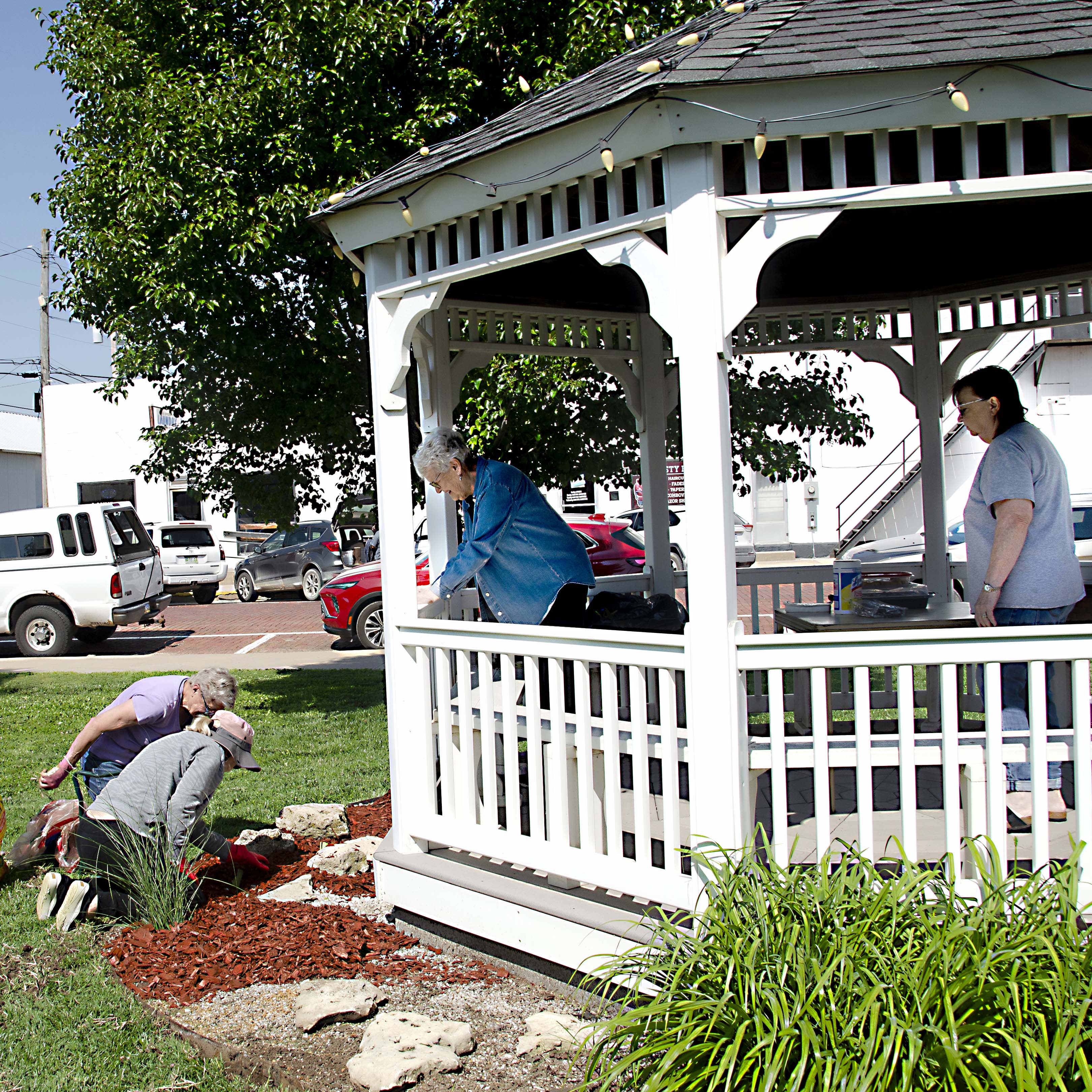 Volunteers from Emmanuel Baptist Church beautify a gazebo Monday in Liberty Park, weeding a garden, planting irises and roses, fertilizing, and renewing mulch. 